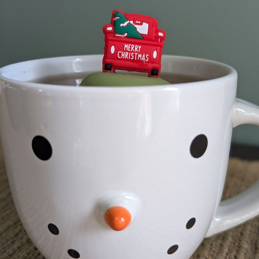red pickup truck with christmas tree in the back and text "merry christmas" on the back tea infuser for loose leaf tea with a fine mesh stainless steel tea strainer that reads FLOAT2INFUSE on a green base floating in a snowman tea cup