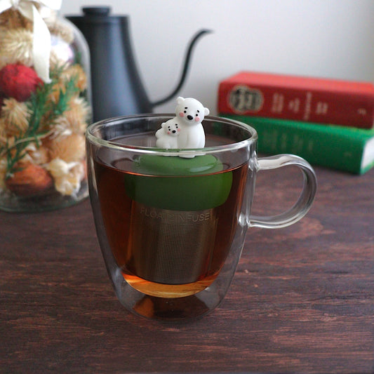cute mom and baby polar bear tea infuser for loose leaf tea with a fine mesh stainless steel tea strainer
that reads FLOAT2INFUSE on a dark green base with a tea kettle, christmas decorations, and books in the background