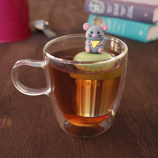adorable grey mouse with yellow cheese wedge tea infuser for loose leaf tea with a fine mesh stainless steel tea strainer
that reads FLOAT2INFUSE on a green base with a tea canister and books in the background