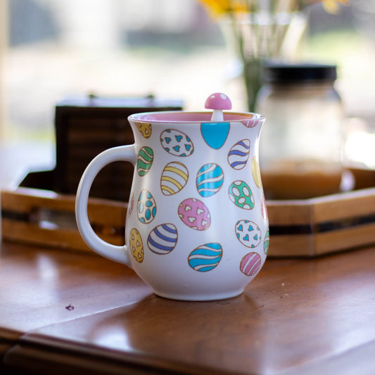 pink mushroom tea infuser for loose leaf tea with a fine mesh stainless steel tea strainer that reads FLOAT2INFUSE on a green base floating in an easter tea mug with a flower vase in the background