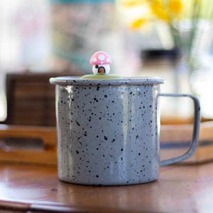 pink mushroom house tea infuser for loose leaf tea with a fine mesh stainless steel tea strainer that reads FLOAT2INFUSE on a green base floating in a speckled blue tea mug 