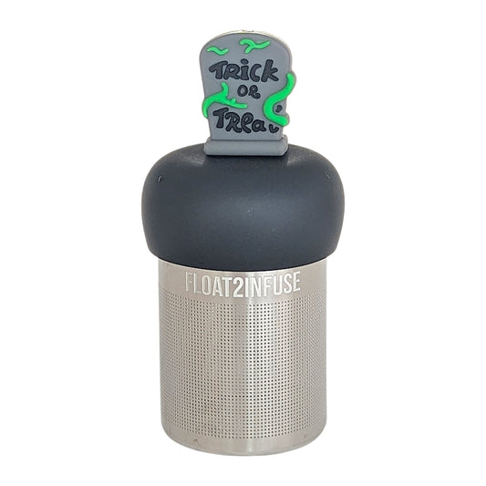 green vines wrap around a halloween themed tombstone with text that reads "trick or treat" tea infuser for loose leaf tea with a fine mesh stainless steel tea infuser that reads FLOAT2INFUSE on a black base with  a white background