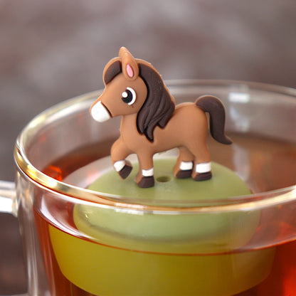 brown horse animal tea infuser for loose leaf tea  with a fine mesh stainless steel tea infuser that reads FLOAT2INFUSE on a green base floating in a glass tea mug