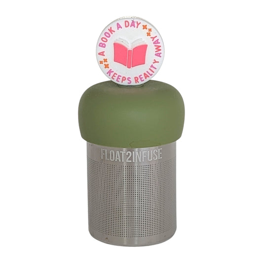 white circle that reads "a book a day keeps the reality away" with a centered pink book tea infuser for loose leaf tea  with a fine mesh stainless steel tea infuser that reads FLOAT2INFUSE on a green base on a white background