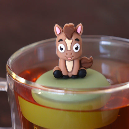 brown donkey animal tea infuser for loose leaf tea  with a fine mesh stainless steel tea infuser that reads FLOAT2INFUSE on a green base floating in a glass tea mug