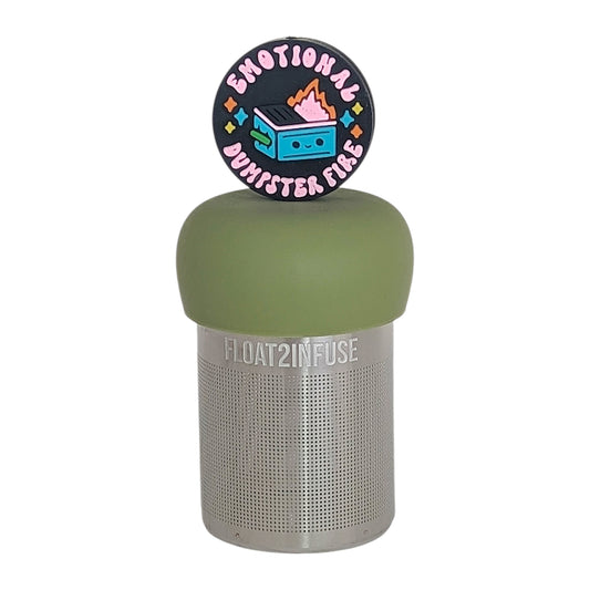 black circle with text that reads "emotional dumpster fire" and an image of a smiling dumpster fire tea infuser for loose leaf tea  with a fine mesh stainless steel tea infuser that reads FLOAT2INFUSE on a green base with a white background