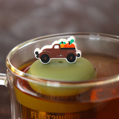 brown pumpkin truck tea infuser for loose leaf tea with a fine mesh stainless steel tea infuser that reads FLOAT2INFUSE on a green base  floating in a glass tea mug 