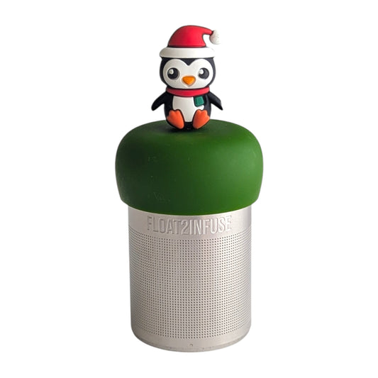 Black and white penguin wearing a red santa hat and a red and green scarf tea infuser for loose leaf tea with a fine mesh stainless steel tea strainer that reads FLOAT2INFUSE on a dark green base with a white background