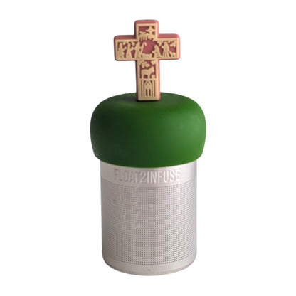 Nativity scene on a warm pink cross tea infuser for loose leaf tea with a fine mesh stainless steel tea strainer that reads FLOAT2INFUSE on a dark green base with a white background