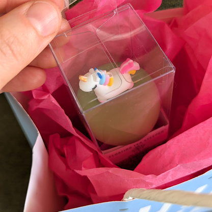 someone is unwrapping a floating unicorn tea infuser in a gift bag