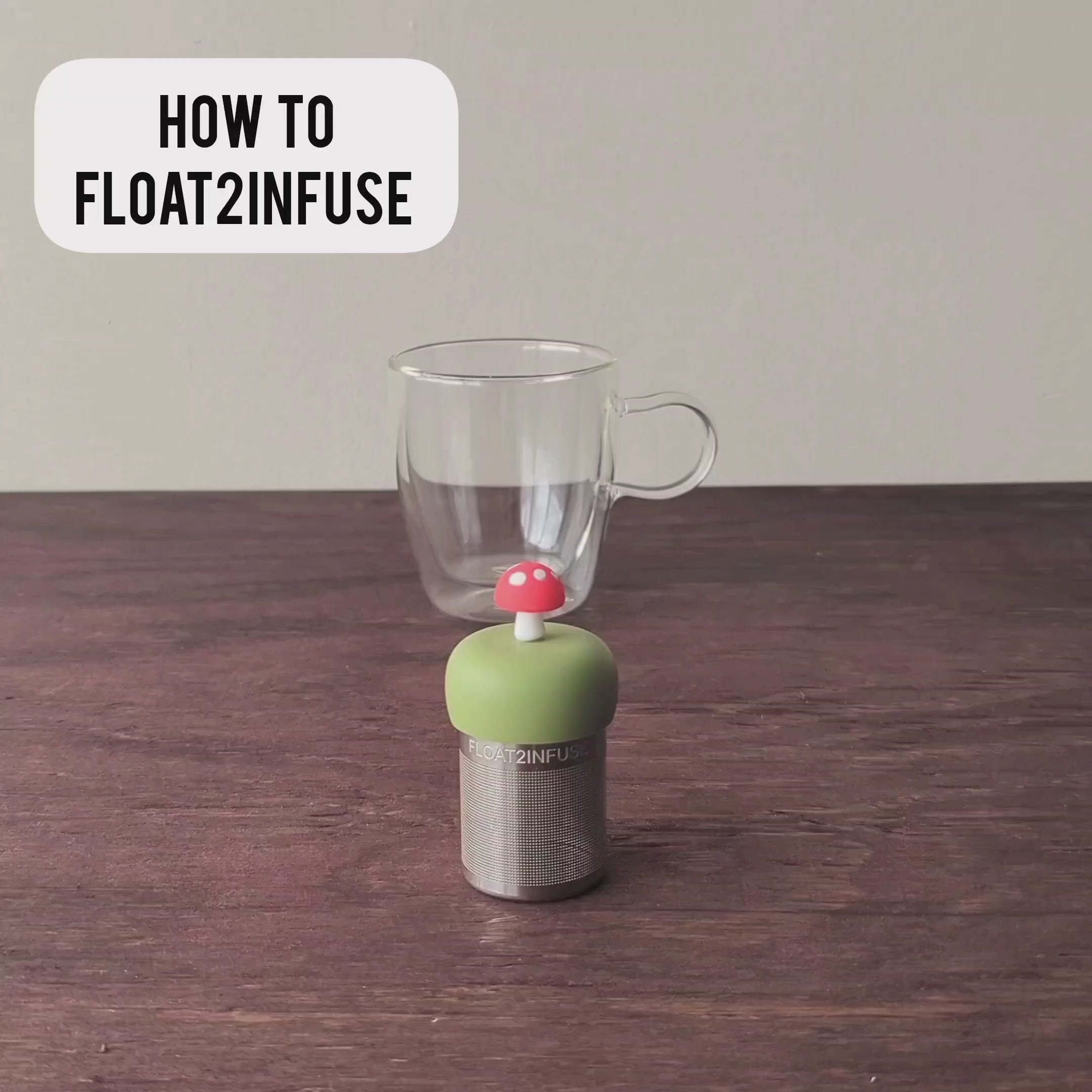 Load video: This video is a step by step tutorial for our easy to use a Float2infuse tea infuser. The tea infuser is sitting on a wooden table. A person takes the tea infuser apart. A person puts 3 teaspoons of loose tea leaves into the leak proof stainless steel fine mesh tea strainer. The green silicone floater of the red mushroom tea infuser is pushed onto the tea basket. The floating tea infuser is placed in a glass mug. hot water is poured into the glass tea cup using a goose neck tea kettle. the floating tea infuser immediately floats and infuses the water to brew hot tea.