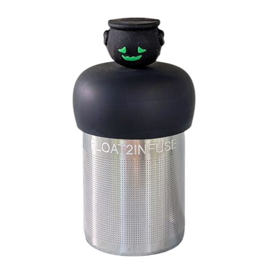 Front view of a black cauldron with a green smiling face tea infuser for loose leaf tea with a fine mesh stainless steel tea strainer that reads FLOAT2INFUSE on a black base  with a white background
