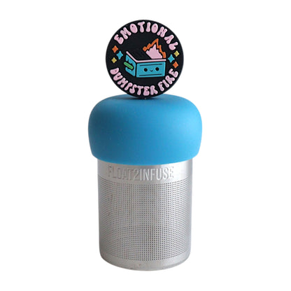 black circle with text that reads "emotional dumpster fire" and an image of a smiling dumpster fire tea infuser for loose leaf tea  with a fine mesh stainless steel tea infuser that reads FLOAT2INFUSE on a green base with a white background