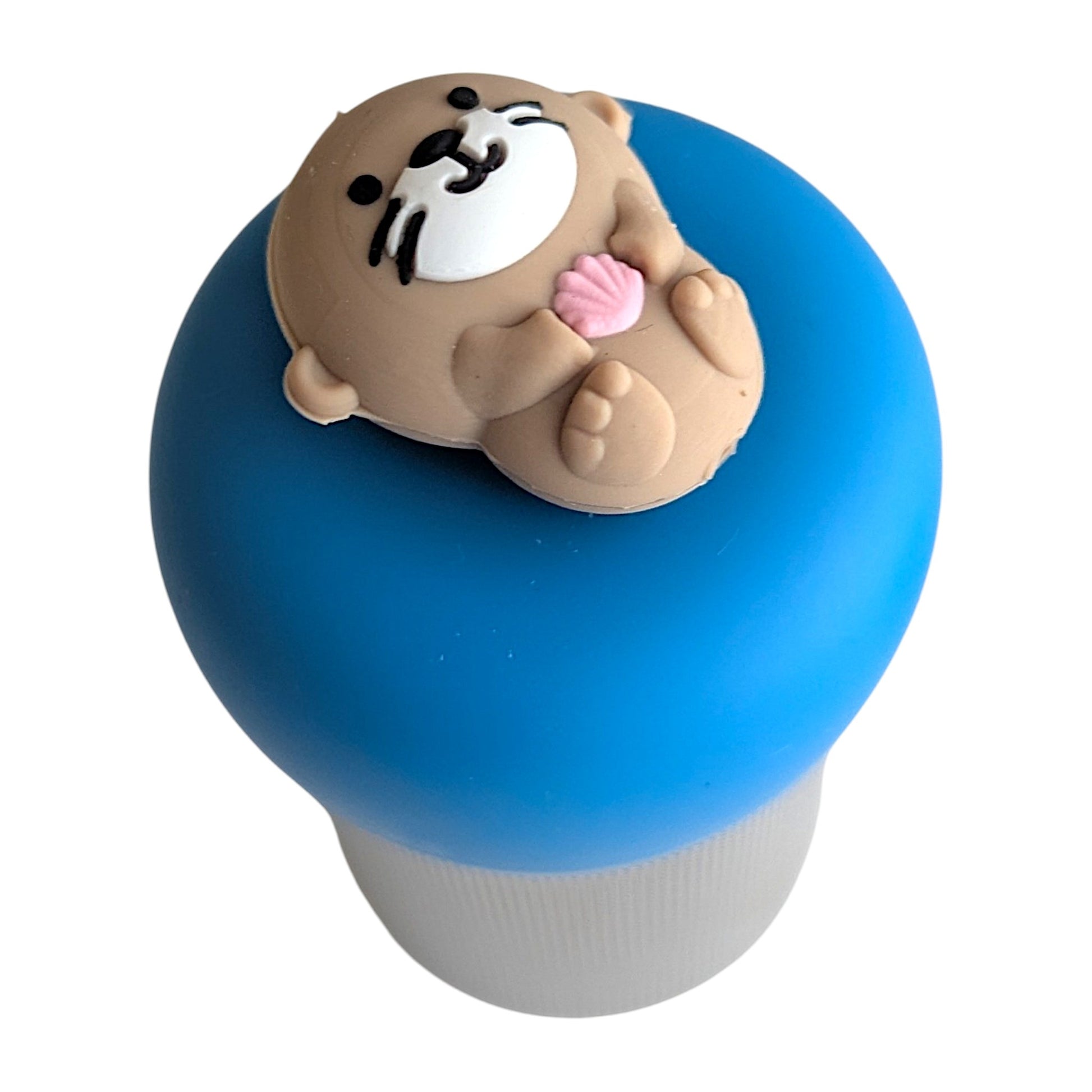 cute little otter floating on it's back holding a pink seashell tea infuser for loose leaf tea with a fine mesh stainless steel tea strainer 
that reads FLOAT2INFUSE on a blue base with a white background