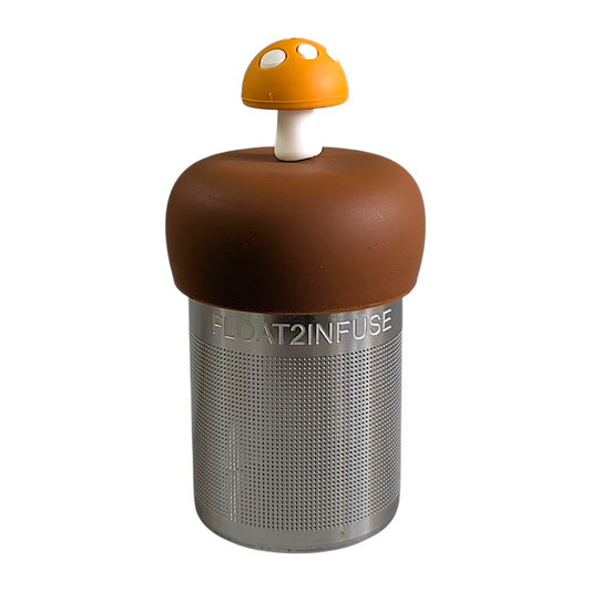amber yellow mushroom with white dots tea infuser for loose leaf tea with a fine mesh stainless steel tea strainer that reads FLOAT2INFUSE on a brown base with a white background