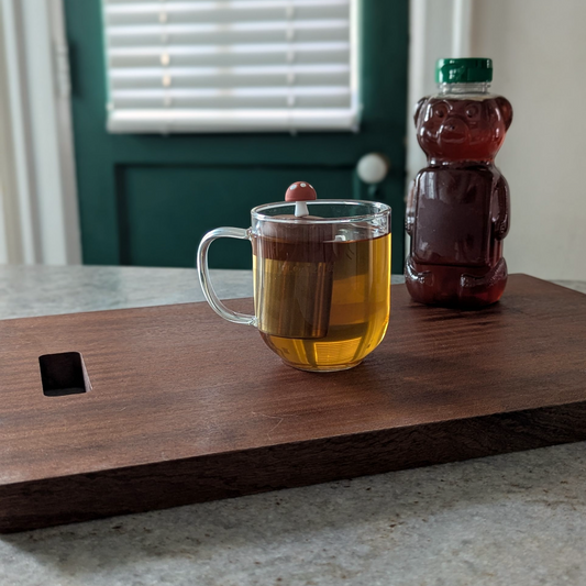 chestnut brown mushroom tea infuser for loose leaf tea with a fine mesh stainless steel tea strainer 
that reads FLOAT2INFUSE on a brown base floating in a glass tea mug 
with a honey bear in the background
