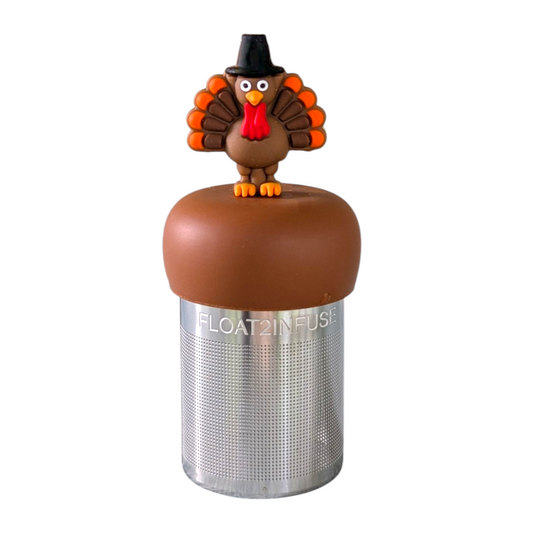 Thanksgiving turkey wearing a black pilgrim top hat tea infuser for loose leaf tea with a fine mesh stainless steel tea strainer that reads FLOAT2INFUSE on a brown base  with a white background