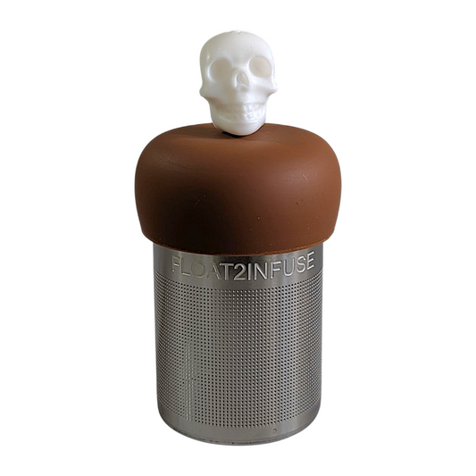 white skull tea infuser for loose leaf tea with fine mesh stainless steel tea strainer that reads FLOAT2INFUSE on a brown base with a white background