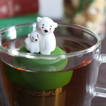 cute mom and baby polar bear tea infuser for loose leaf tea with a fine mesh stainless steel tea strainer 
that reads FLOAT2INFUSE on a dark green base with a tea canister and books in the background