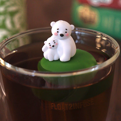 cute mom and baby polar bear tea infuser for loose leaf tea with a fine mesh stainless steel tea strainer 
that reads FLOAT2INFUSE on a dark green base with a tea canister and books in the background