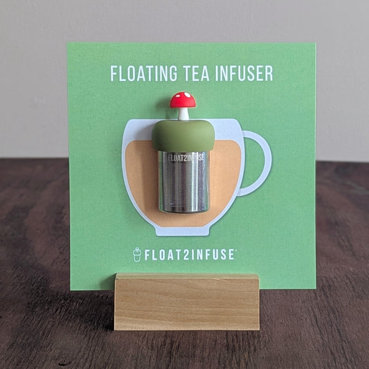 Floating red mushroom tea infuser on a green card with 'FLOAT2INFUSE' branding