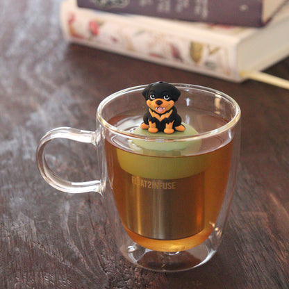 black and tan rottweiler dog animal tea infuser for loose leaf tea on a green base with a fine mesh stainless steel tea infuser that reads FLOAT2INFUSE floating in a glass tea mug with books in the background