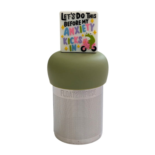 White square with text "let's do this before my anxiety kicks in" with a green frog riding a pink bike tea infuser for loose leaf tea with a fine mesh stainless steel tea strainer that reads FLOAT2INFUSE on a green base with a white background