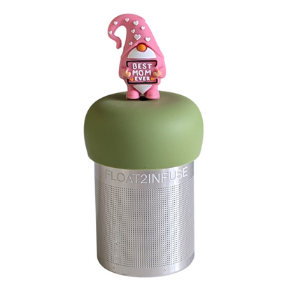 gnome with long white beard wearing pink clothing with white hearts holding a sign with the text "best mom ever"  tea infuser for loose leaf tea with a fine mesh stainless steel tea strainer 
that reads FLOAT2INFUSE on a green base with a white background