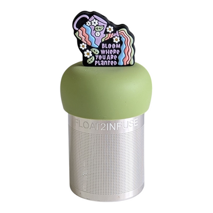 colorful watering can with daisies and leaves and the text "bloom where you are planted" tea infuser for loose leaf tea with a fine mesh stainless steel tea strainer that reads FLOAT2INFUSE on a green base with a white background