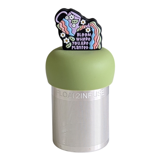 colorful watering can with daisies and leavesand the text "bloom where you are planted" tea infuser for loose leaf tea with a fine mesh stainless steel tea strainer that reads FLOAT2INFUSE on a green base with a white background