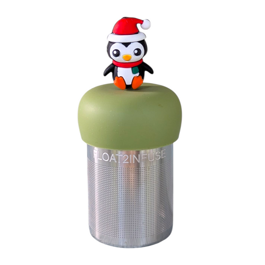 Black and white penguin wearing a red santa hat and a red and green scarf tea infuser for loose leaf tea with a fine mesh stainless steel tea strainer that reads FLOAT2INFUSE on a green base with a white background