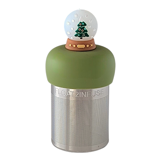 snowglobe with a christmas tree inside for loose leaf tea with fine mesh stainless steel tea strainer that reads FLOAT2INFUSE on a green base with a white background