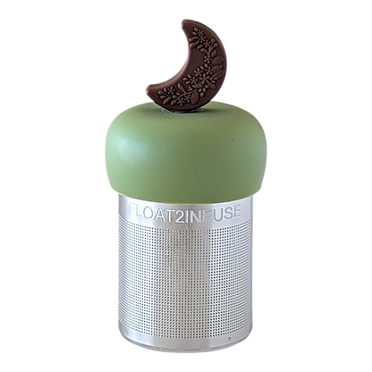 Brown crescent moon with floral pattern tea infuser for loose leaf tea with a fine mesh stainless steel tea strainer  that reads FLOAT2INFUSE on a green base with a white background