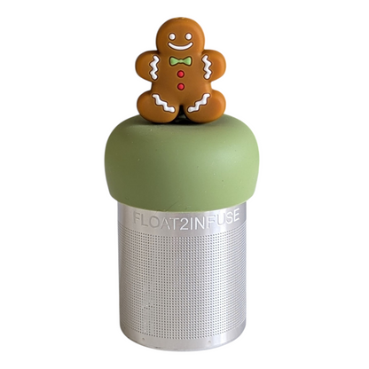 smiling gingerbread man with green bowtie, red buttons and white accents tea infuser for loose leaf tea with a fine mesh stainless steel tea strainer that reads FLOAT2INFUSE on a green base with a white background