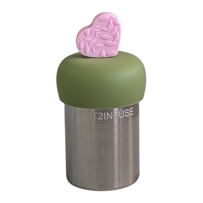 pink colored heart with leafy pattern tea infuser  for loose leaf tea with fine mesh stainless steel tea strainer that reads FLOAT2INFUSE on a green base with a white background