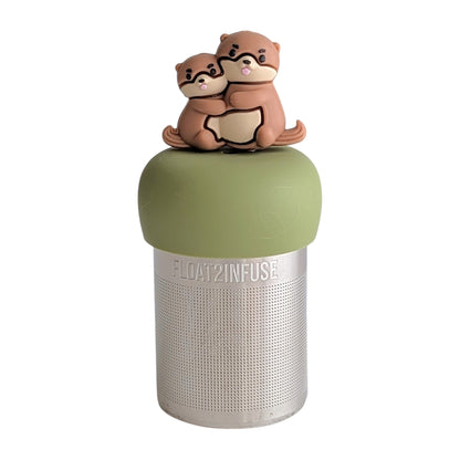 Brown otter momma hugging her baby tea infuser for loose leaf tea with a fine mesh stainless steel tea strainer that reads FLOAT2INFUSE on a green base with a white background