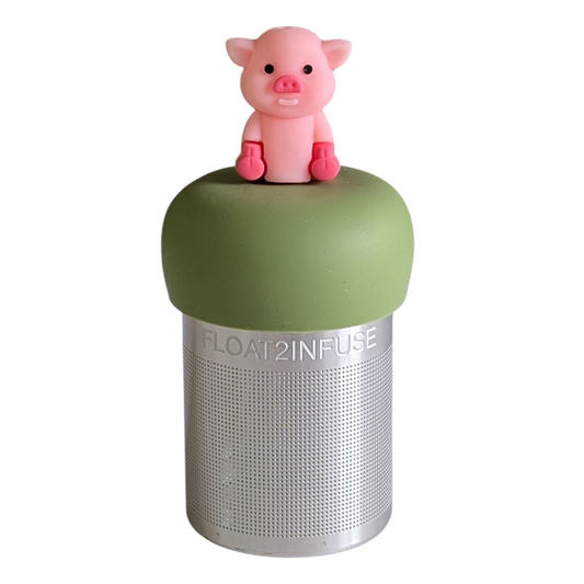 pink pig animal tea infuser for loose leaf tea with a fine mesh stainless steel tea strainer that reads FLOAT2INFUSE on a green base with a white background