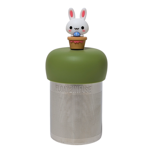 White bunny in flower pot holding blue egg tea infuser  for loose leaf tea with a fine mesh stainless steel tea strainer that reads FLOAT2INFUSE on a green base with a white background