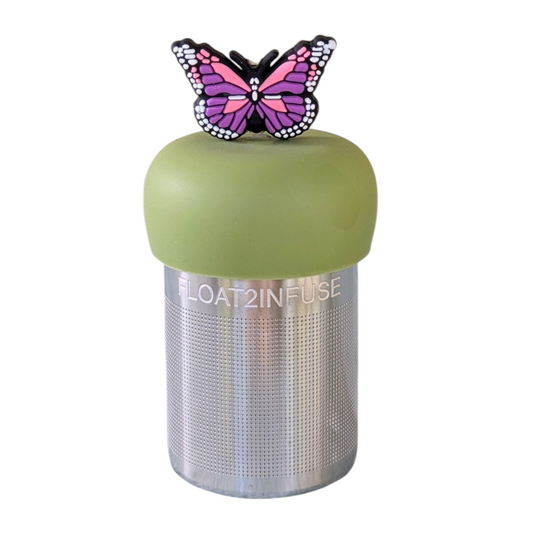 Purple and pink butterfly tea infuser for loose leaf tea with a fine mesh stainless steel tea strainer that reads FLOAT2INFUSE on a green base  with a white background