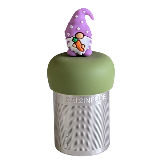 gnome with a long white beard and wearing light purple clothing holding an orange carrot tea infuser for loose leaf tea on a green base with a fine mesh stainless steel strainer that reads FLOAT2INFUSE with a white background