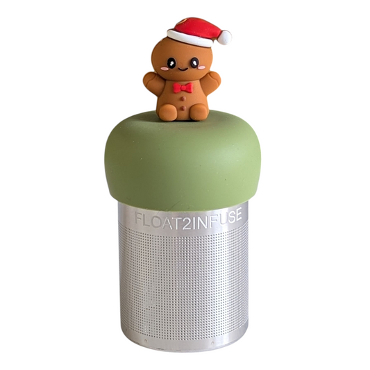 happy gingerbread man with a red bowtie and wearing a red and white santa hat tea infuser for loose leaf tea with a fine mesh stainless steel tea strainer that reads FLOAT2INFUSE on a green base with a white background