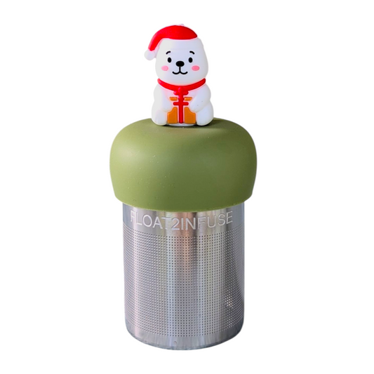 Smiling white polar bear holding a present and wearing a red santa hat tea infuser for loose leaf tea with a fine mesh stainless steel tea strainer that reads FLOAT2INFUSE on a green base  with a white background