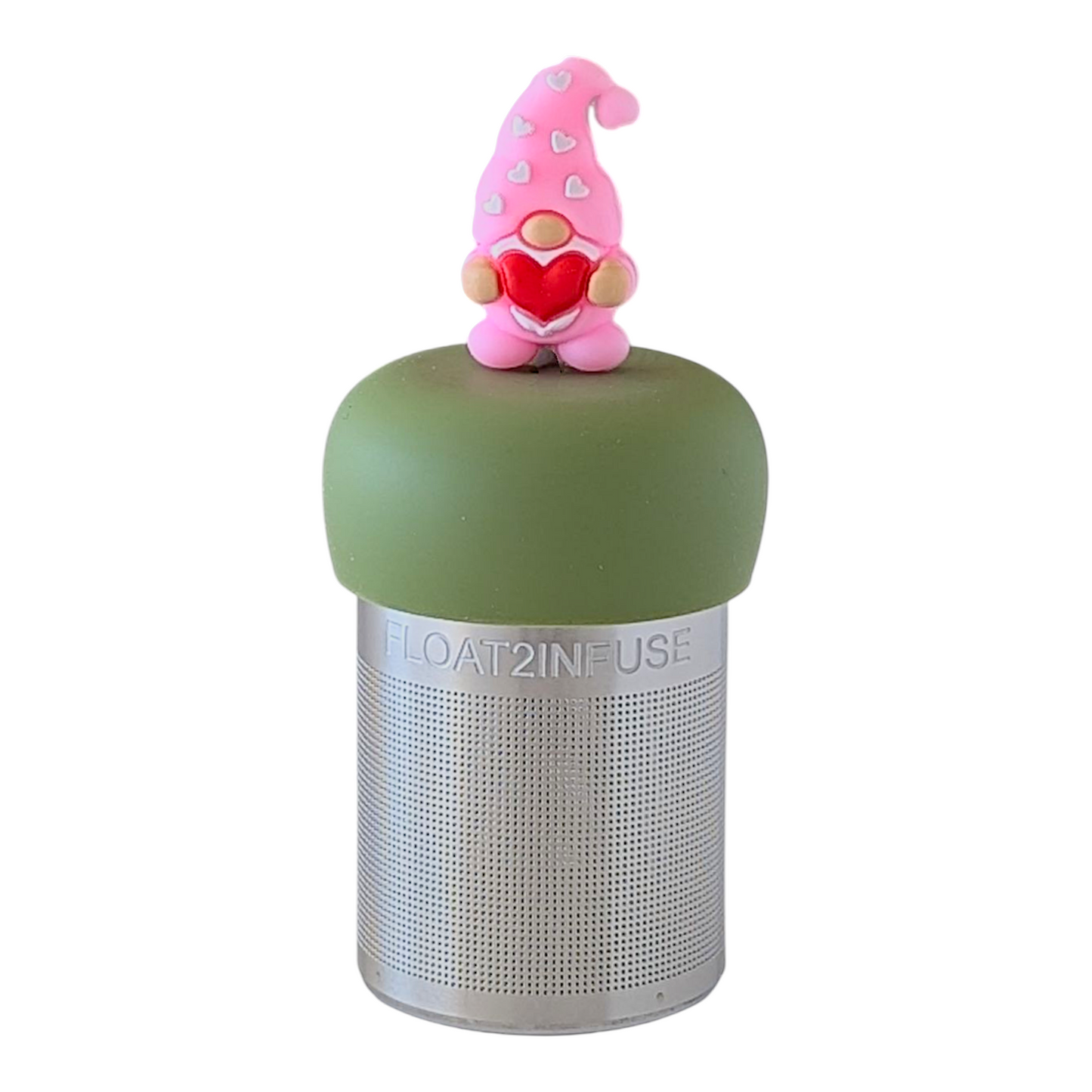pink gnome holding a red heart tea infuser for loose leaf tea with a fine mesh stainless steel tea strainer that reads FLOAT2INFUSE on a green base with a white background