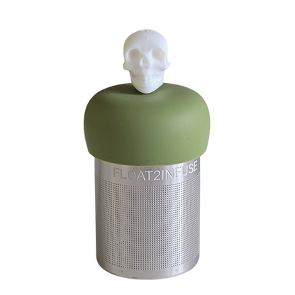 white skull tea infuser for loose leaf tea with a fine mesh stainless steel tea strainer that reads FLOAT2INFUSE on a green base with a white background